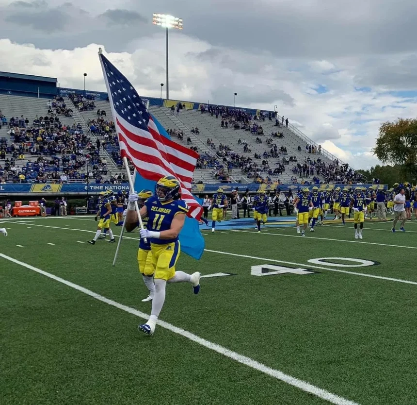 College football player celebrating win by running across field with American flag