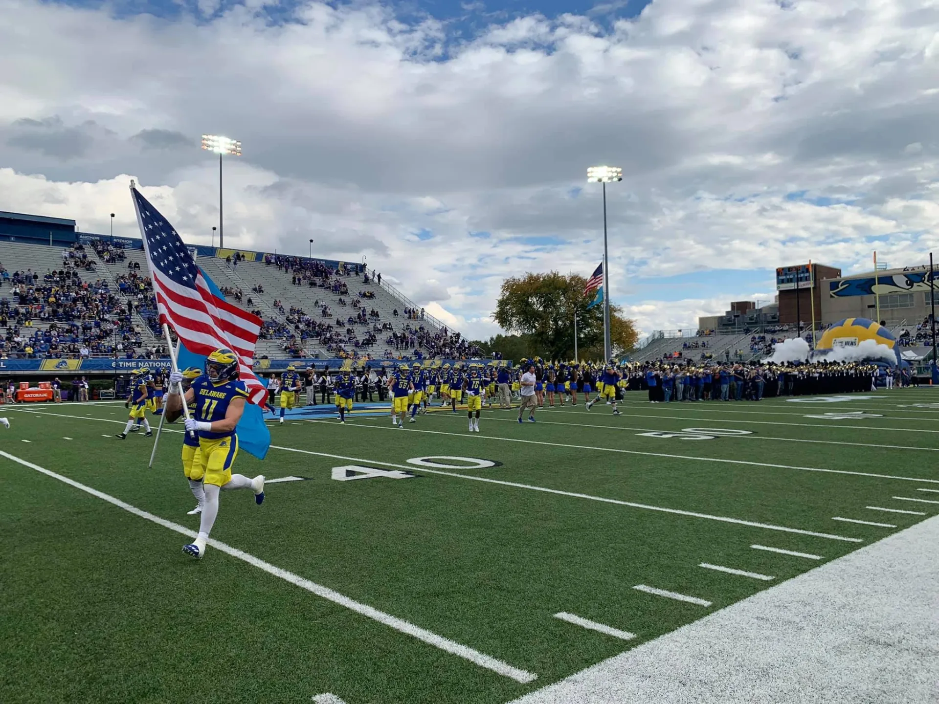 Unversity of Delaware football player carrying American flag down field