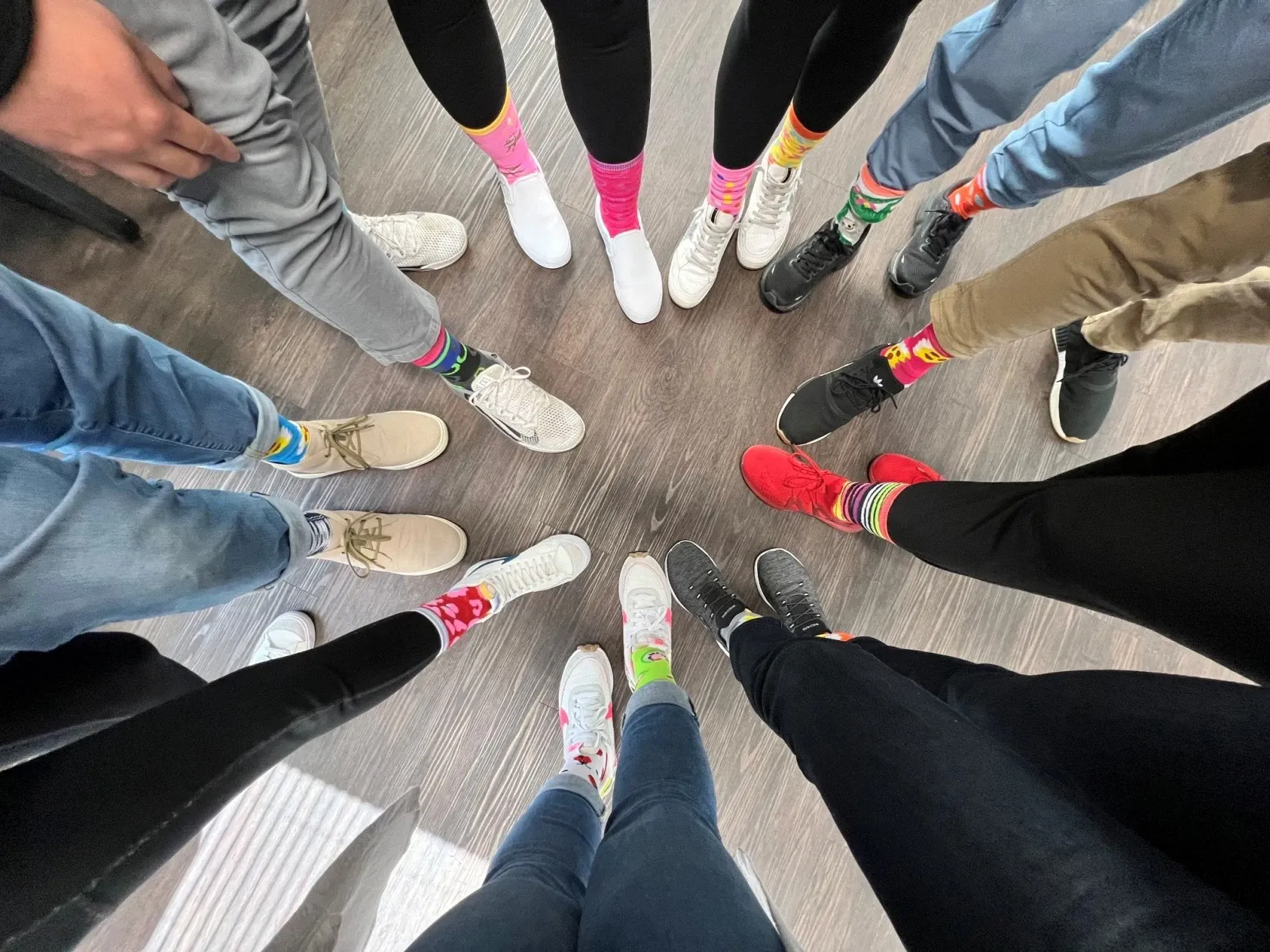 Perspective shot of a group of people putting their feet in a circle to show off their socks
